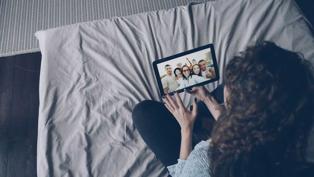 A welcoming host smiles while using a tablet, representing direct and positive communication with their list of valued guests.